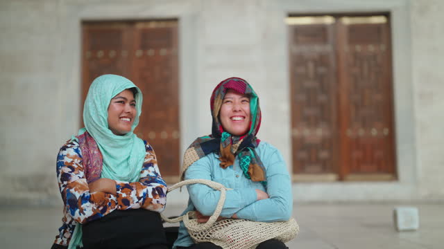 Two multiethnic female tourist friends visiting Istanbul and Blue Mosque in Türkiye Turkey