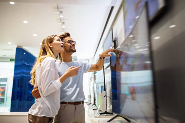 istock Young couple in consumer electronics store looking at latest digital devices, television. 2005229749
