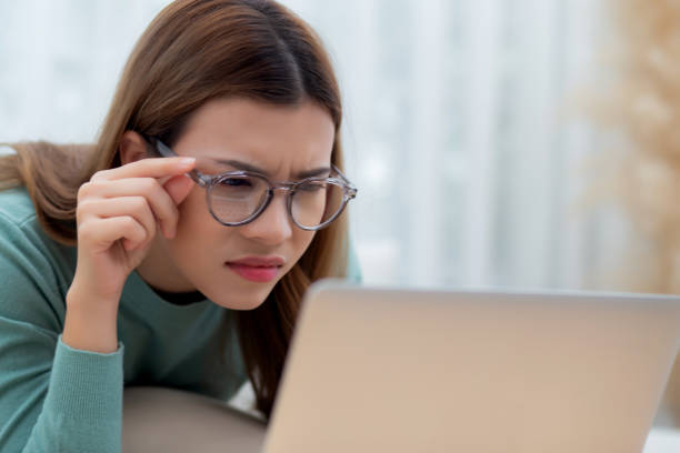 istock Concentrated young asian woman wearing glasses working on laptop with commitment and ambition sitting on sofa in living room at home, work from home, freelance working online, business and lifestyle. 2005231333