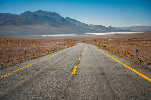 low angle view on lonely country road in the atacama desert with mountain range in the background
