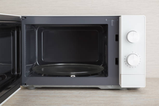 istock New white microwave oven with opened door on table top at home kitchen. Empty glass plate inside for food. Closeup. Front view. 2005244646