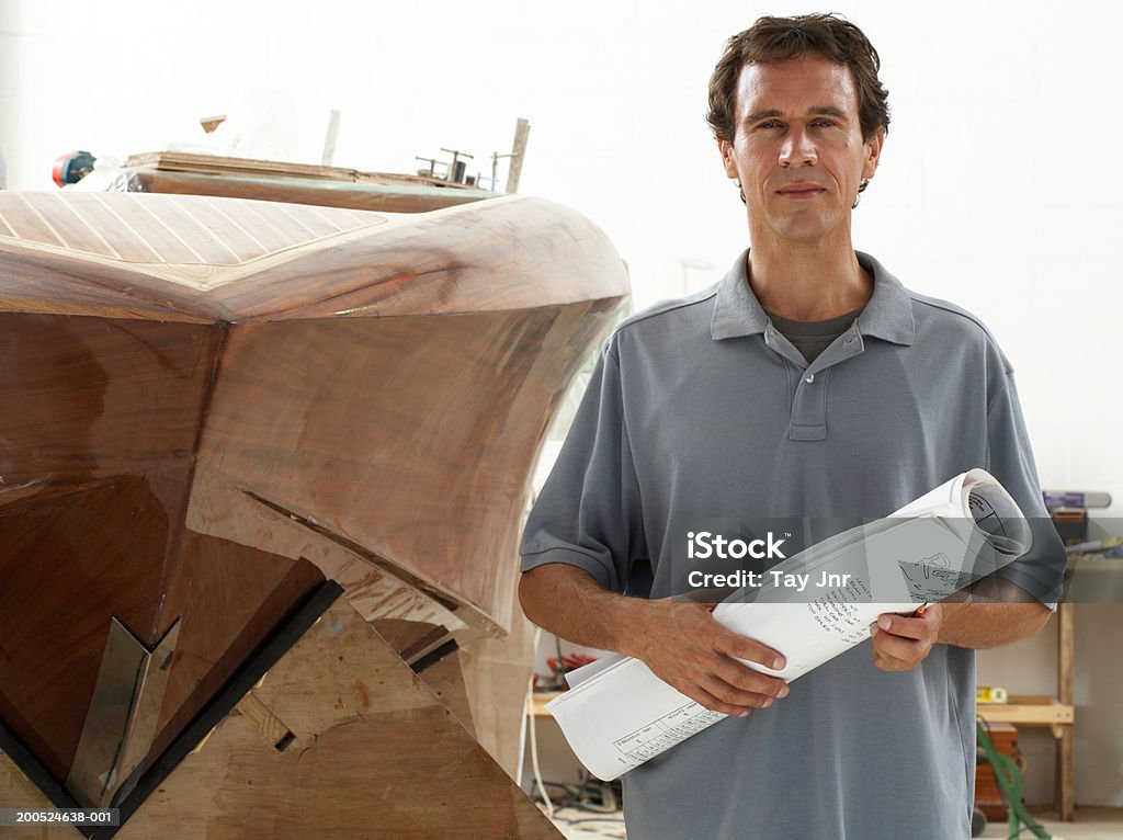 Hombre que agarra planos en embarcación edificio de taller, retrato - Foto de stock de 35-39 años libre de derechos