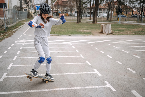 Girl learning skateboarding in public park
