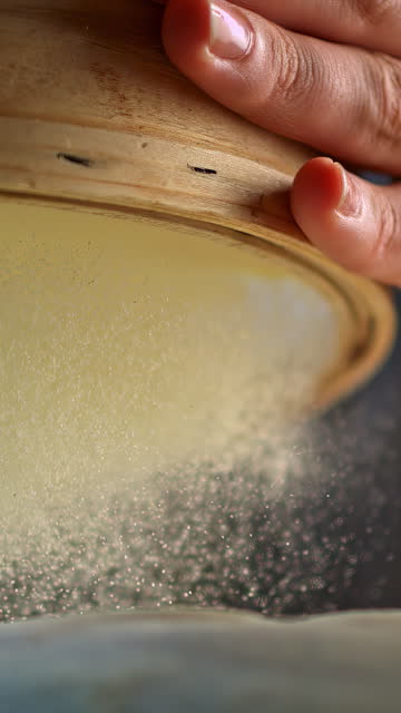 Person sifting white flour for baking. Human hands holding a wooden sieve