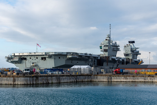 Portsmouth, UK - February 11th 2024: The HMS Queen Elizabeth, a Queen Elizabeth Class aircraft carrier moored at the Royal Naval base viewed from the Historic Dockyard.