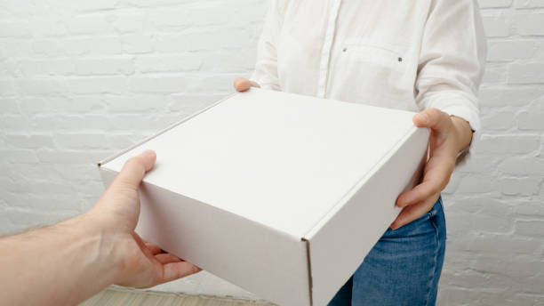 istock Young woman receiving parcel from delivery man, white brick background. 2005313231