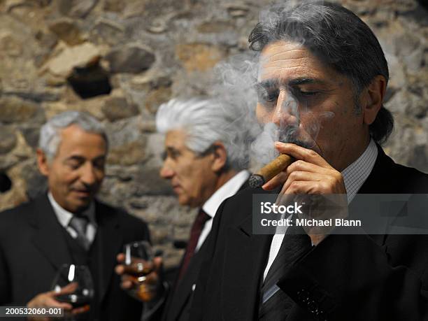 Photo libre de droit de Homme Daffaires De Fumer Un Cigare Dans Le Restaurant Hommes Daffaires En Backgrou banque d'images et plus d'images libres de droit de Cigare