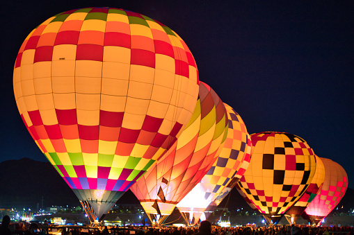 Several hot air balloons illuminated in the darkness awaiting liftoff in New Mexico