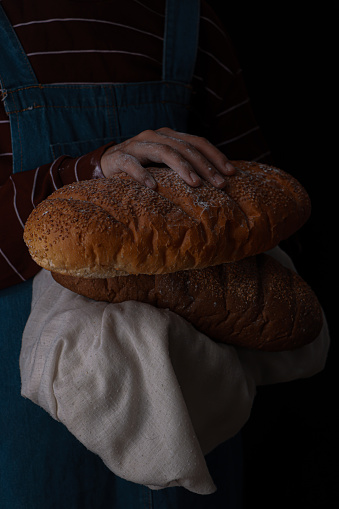 A woman in a striped shirt grasps two loaves of bread.
