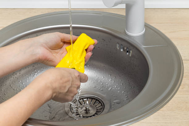 istock female hand wets a rag under running water in the kitchen. 2005331265