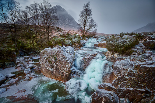 Buachaille Etive Mor and the River Coupall, Glen Etive, Western Highlands, Scotland during winter, the waterfall is partly frozen.