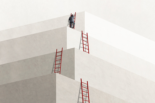 A businessman climbs the last of a series of ladders to reach his goal.