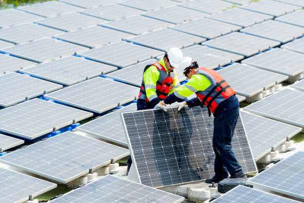 istock Two Asian technician workers stand and help to install or set up solar panels over water reservoir in the plant for green energy factory system workplace. 2005414592