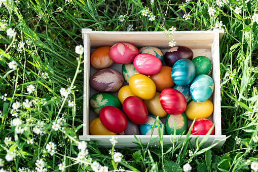 Stylish Easter eggs and spring flowers on rustic table. Happy Easter! Natural dye marble and blue eggs in tray and daffodils bouquet. Happy Easter! Holiday minimal still life