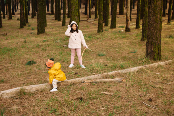 Brothers playing in the forest with bow and logs