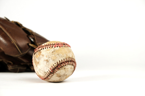 Used texture of baseball with ball glove blurred in background, isolated on white backdrop.