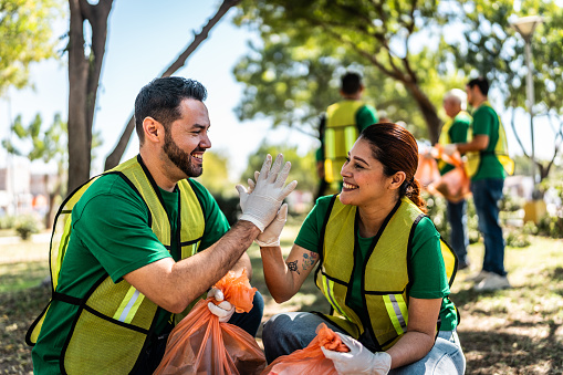 Recyclers doing high-five and cleaning the public park