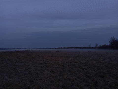 Evening landscape at sunset. A thick fog descended on the ground. Beautiful field landscape on a grassy field.