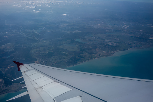 passenger point of view wing of airplane sea and land are background horizontal travel still