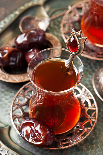 Turkish  tea in glass cup  with date fruit in traditional copper serving set,  selective focus with shallow depth of field