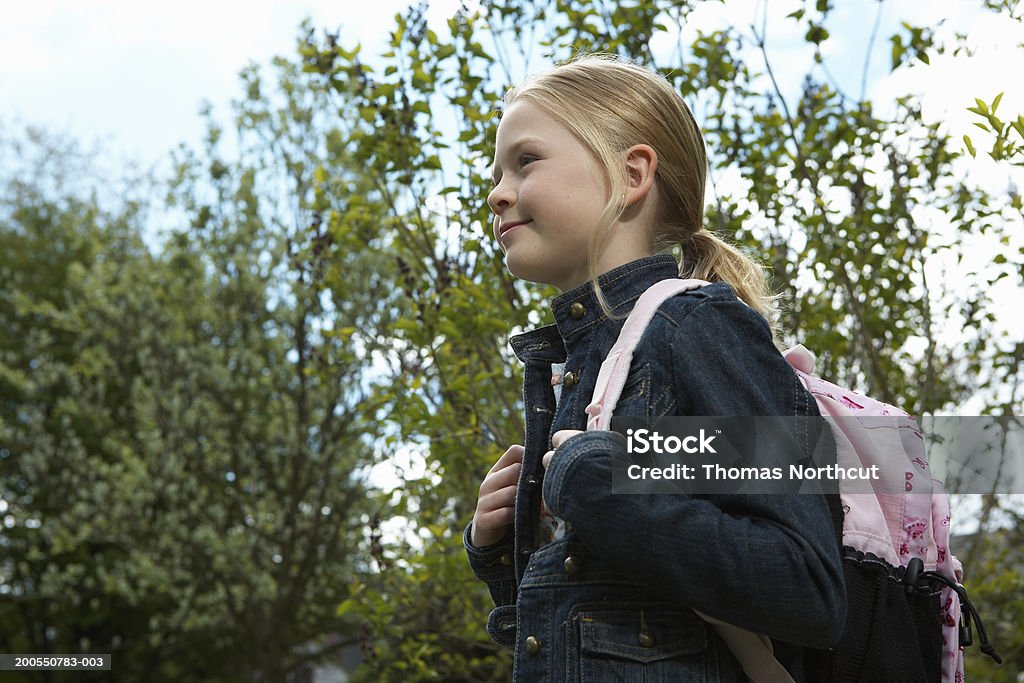 Girl (8-10) carrying backpack outdoors, smiling, side view  Backpack Stock Photo