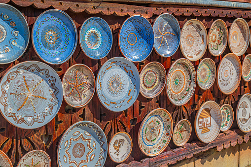 Romanian traditional ceramic plates from Horezu area, Romania, placed ornamentally on a rustic wooden wall at house.