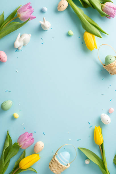 istock Springtime splendor: tiny ceramic bunnies, fresh tulips, sprinkles, and eggs on a pastel blue canvas. Capture the essence of Easter with this delightful table vertical top view arrangement 2005516142