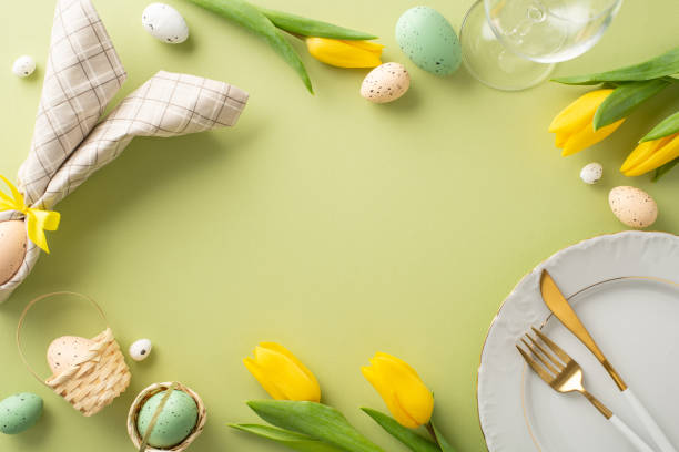 istock Easter Delight Setting: Overhead snapshot showcasing a plate, bunny ear napkin, cutlery, wine glass, tulips, and eggs on a pastel green background. Perfect for creating an Easter vibe in your messages 2005516154