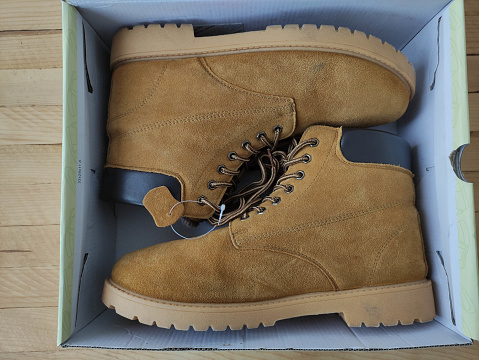 Yellow suede boots in the box on the wooden background