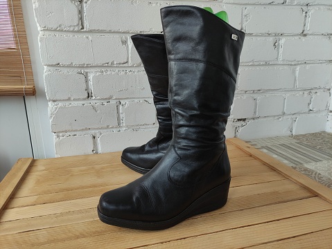 Black leather women's winter boots on a wooden background