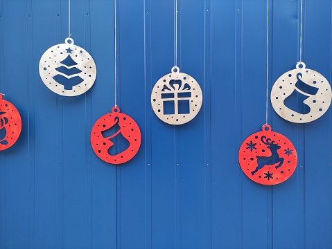 Christmas tree toys on the street sway in the wind on a blue background, at a slight angle