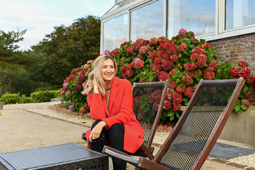 A girl in a red coat sits in a cafe on the terrace near the hydrangea