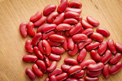 A small group of raw red beans on a wooden background. Top view.