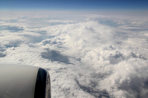 Photo with the view from the porthole of the airplane to the blue sky with white clouds at an altitude of about 10 kilometers
