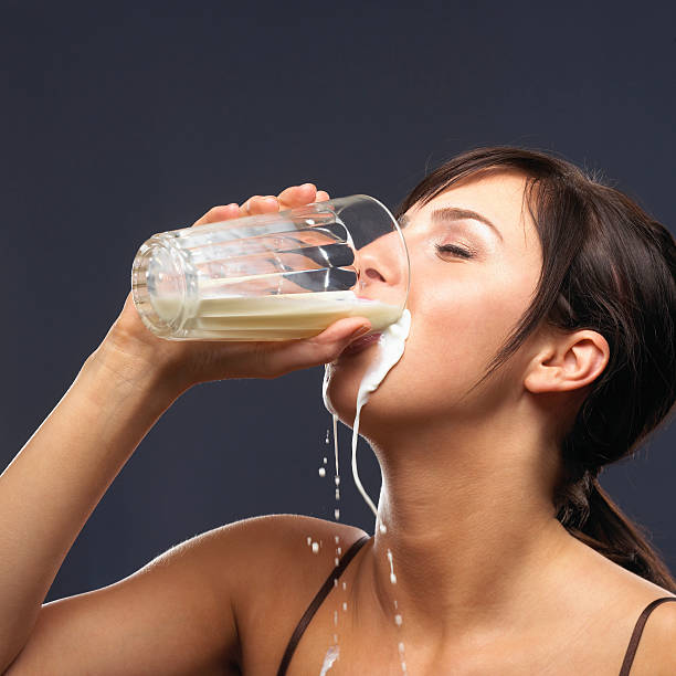 Young woman drinking and spilling milk, close-up, side view  guzzling stock pictures, royalty-free photos & images