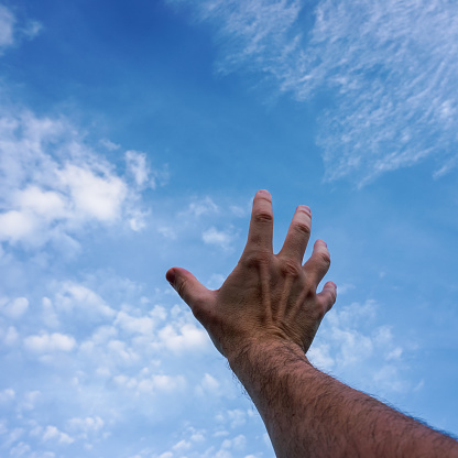 man hand gesturing and reaching the blue sky