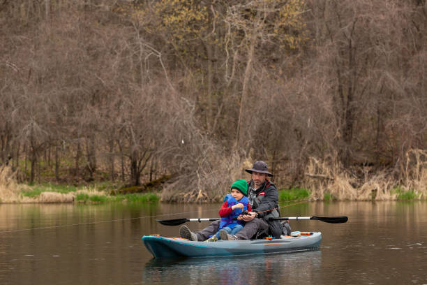 Father & son fishing from their kayak on a springtime day at the lake.