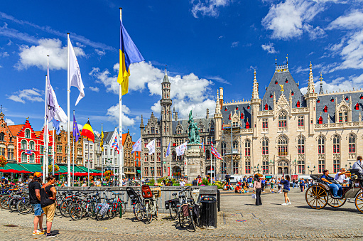 Bruges, Belgium, July 5, 2023: people tourists on Markt square, colorful townhouses buildings, Provinciaal Hof, Historium Bruges historical museum in Brugge old town city centre, Flemish Region