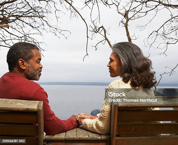 Coppia Matura Seduto Sulla Panchina Di Mare Sorridente Vista Posteriore - Fotografie stock e altre immagini di Ambientazione esterna