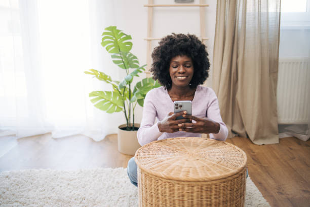 istock Beautiful woman browsing internet on smartphone in living room. 2005676609