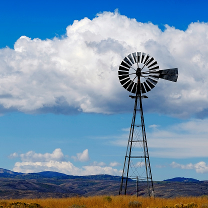 Windmill on hillside in countryside rural America with sky and clouds