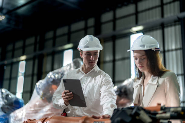 istock Factory engineers inspecting on machine with smart tablet. Worker works at machine robot arm. The welding machine with a remote system in an industrial factory. Artificial intelligence concept. 2005685514