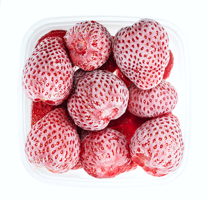 Plastic container with frozen strawberries. Top view of raw fruits isolated on white background. Storage for winter storage in trays