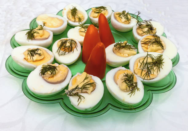 Boiled eggs with paprika and dill in a green tray on a tablecloth