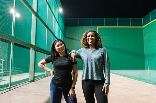 Embracing an active lifestyle beyond work or school hours, two young women dedicate time to their fitness regimen, starting with a series of stretches and warm-up exercises to prime their bodies for movement.