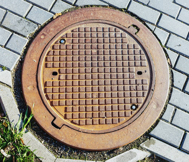 Telecommunication manhole cover on the sidewalk between the tiles during the day