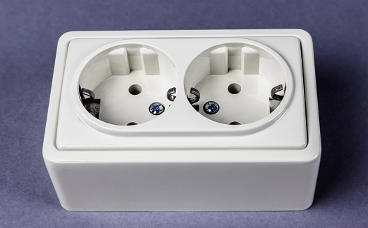 White double socket with earthing on gray background, side view