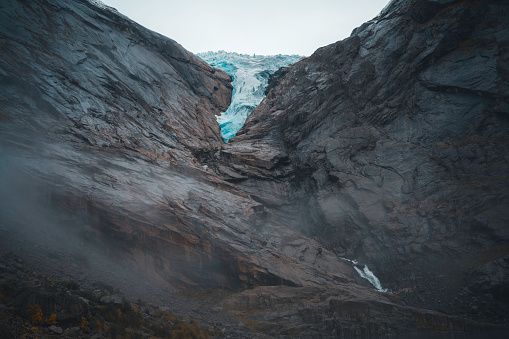 Tongue of the Briksdal glacier, Norway (Briksdalsbreen), on the rocks, with fog and clouds.