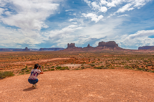 Woman tourist taking photographs of the buttes of the Monument Valley Navajo Tribal Park, Arizona and Utah, USA