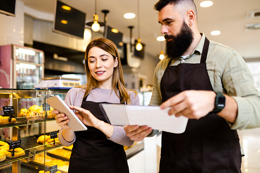 Mid adult  startup partners taking online orders, pastry, and bakery food shop